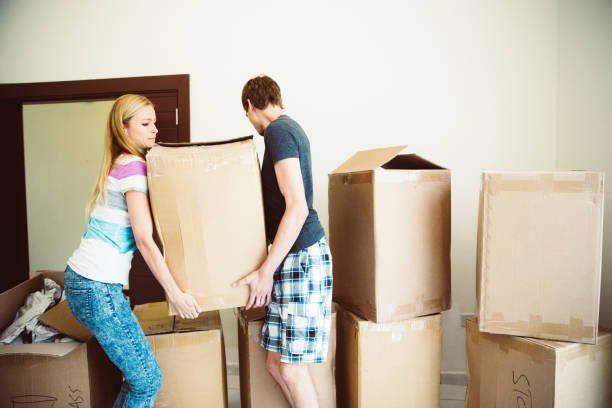 husband and wife working together to move the boxes into the new house.